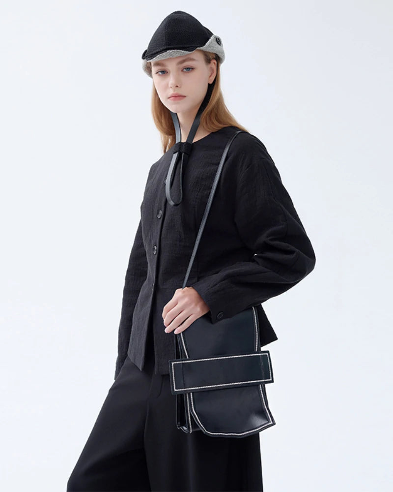 The Somlord 2-in-1 Convertible Leather Mini Backpack styled crossbody on a model wearing a modern black outfit, emphasizing its versatility and sleek structured leather silhouette.