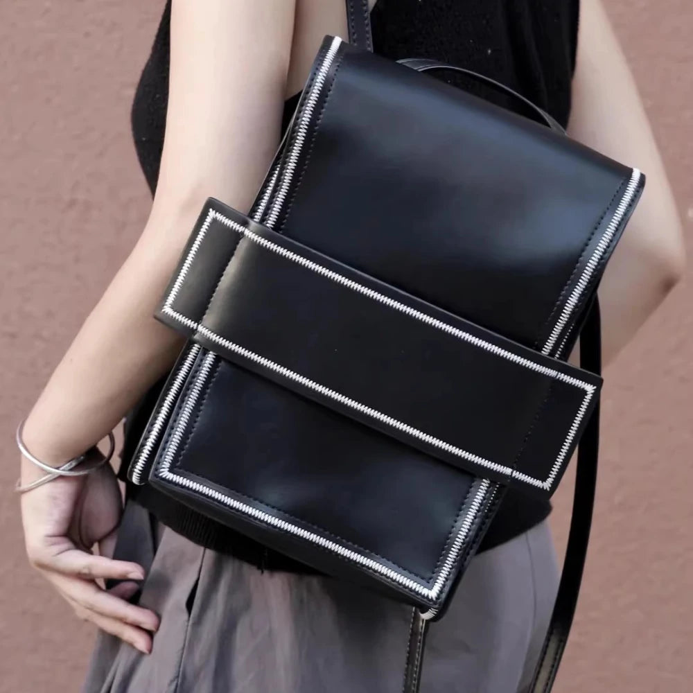 Close-up of the Somlord 2-in-1 Convertible Leather Mini Backpack showcasing its sleek black leather finish and bold, structured design with contrasting white stitching, highlighting the premium craftsmanship and urban minimalist aesthetic.