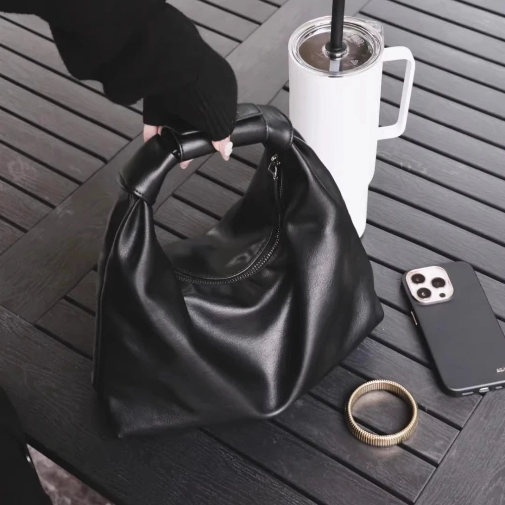 Somlord Black Leather Cloud Hobo Bag – Elegant slouchy leather hobo bag placed on a wooden table, paired with stylish accessories for a modern lifestyle aesthetic.