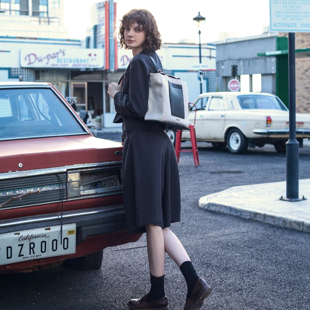 Somlord Urban Hybrid Canvas Structured Tote Backpack – Model walking in an urban setting, showcasing the minimalist black-and-white tote bag, perfect for daily commuting and professional style.