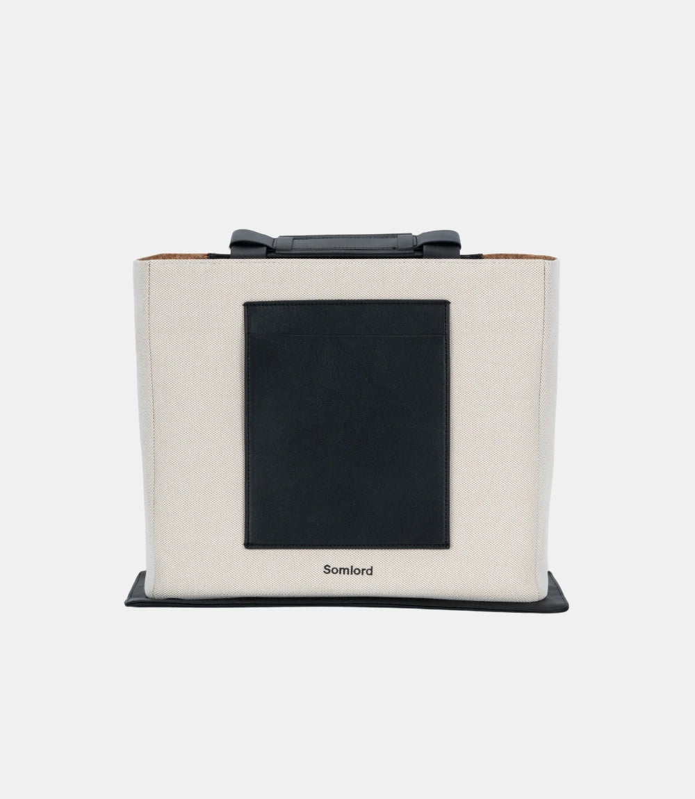Minimalist canvas tote backpack – structured silhouette with a sleek black pocket, ideal for work, travel, and daily essentials.